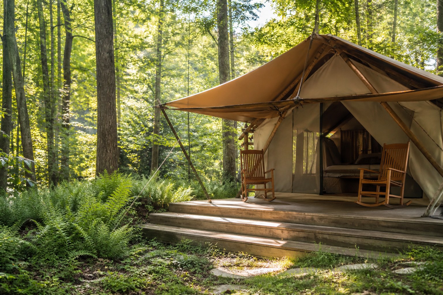 Luxury safari tent on a raised wooden deck among tall trees and ferns in the Ithaca woods