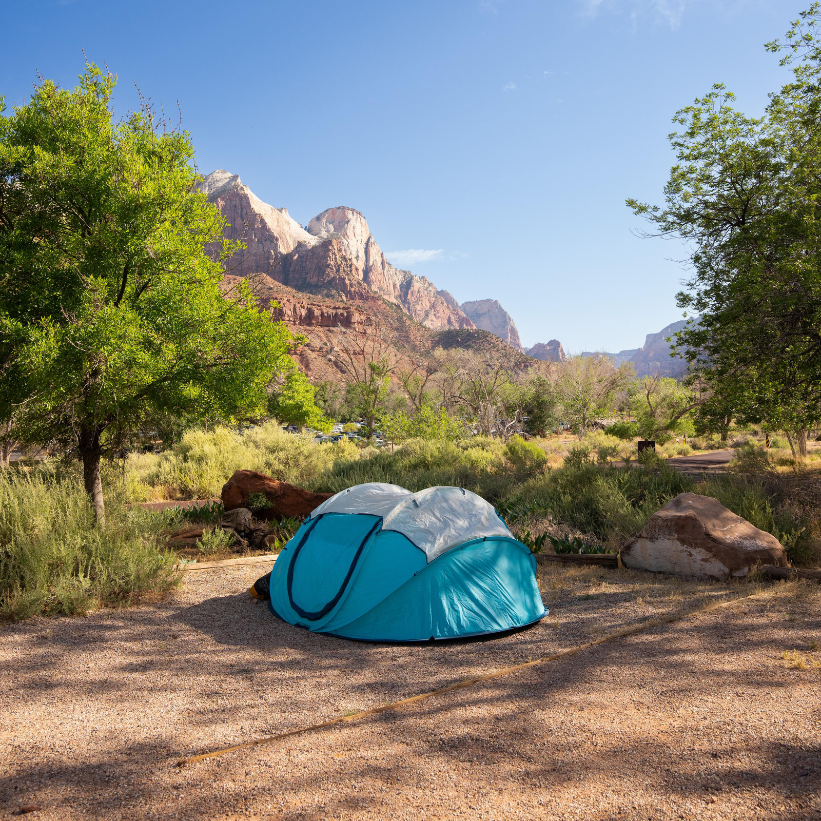 Tent on a gravel pad at Watchman Campground with The Watchman behind it